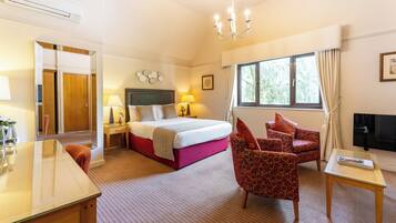 A hotel room with a bed, a desk, a chair, a TV, and a window with curtains.