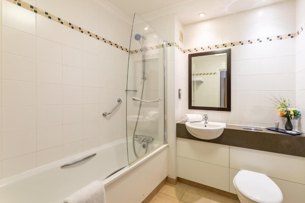 A modern bathroom with a glass-enclosed shower, a bathtub, a sink, and a toilet.