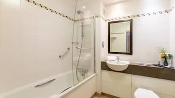 A modern bathroom with a glass-enclosed shower, a bathtub, a sink, and a toilet.