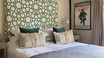 Habitación de hotel con una cama grande, cabecera con diseño circular, dos mesitas de noche con lámparas y un cartel en la pared.