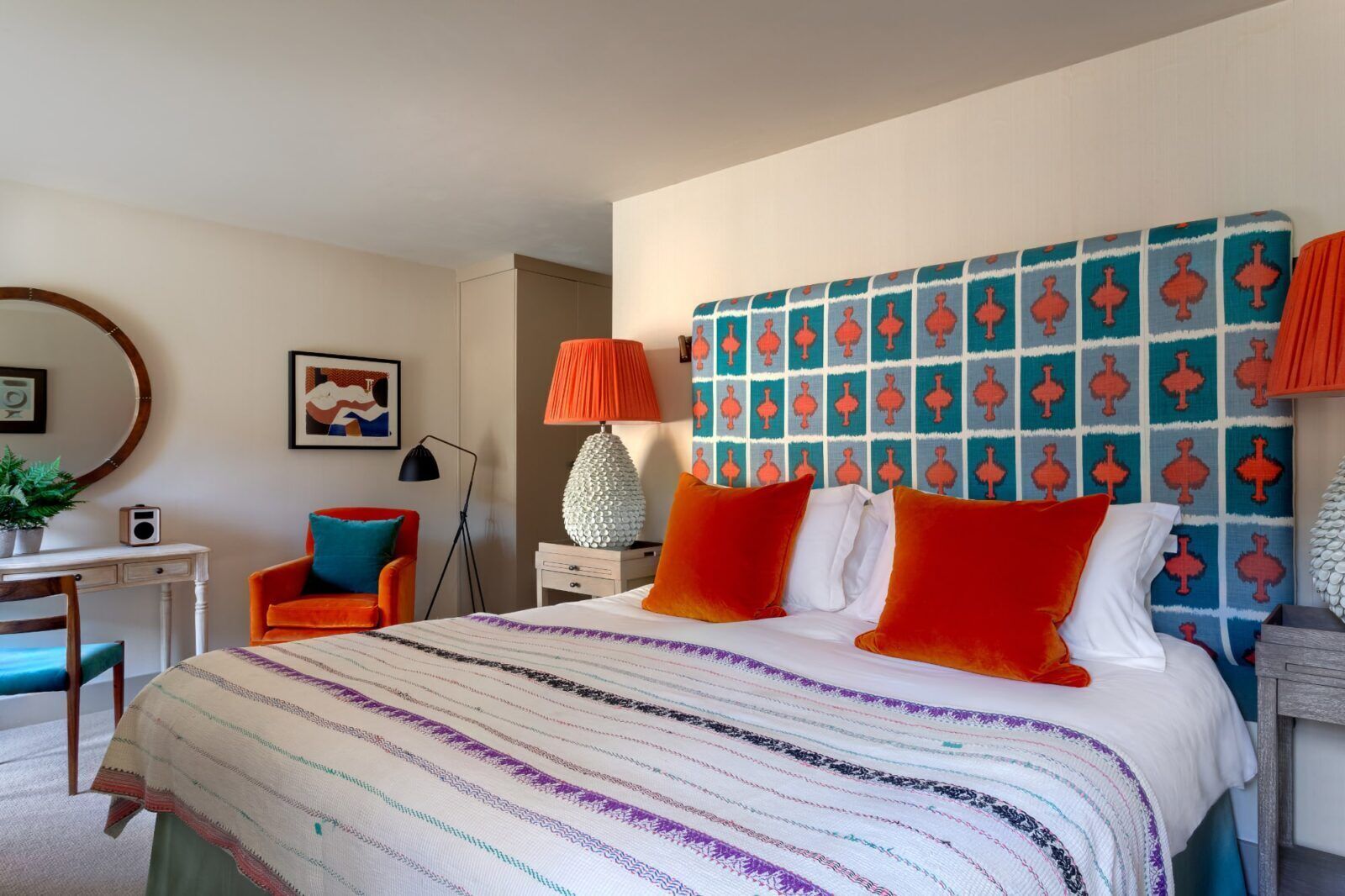 Een slaapkamer met een bed, bureau, stoel en lamp.
