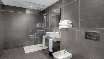 A modern bathroom with a glass-enclosed shower, a sink, and a bidet.