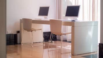 Un espacio de oficina moderno con dos escritorios, cada uno con un monitor de computadora y teclado. Hay dos sillas, una en cada escritorio. La habitación tiene un diseño limpio y minimalista con suelo y paredes de color claro.