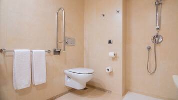 Un baño moderno con inodoro, barra de apoyo, ducha y dos toallas en un perchero.