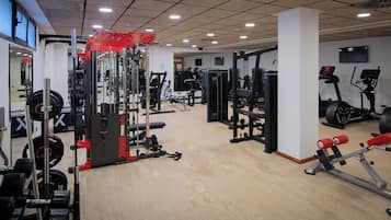 Un gimnasio con diversos equipos de ejercicio, que incluyen máquinas de pesas, cintas de correr y pesas libres.