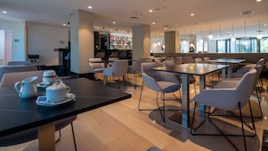 A modern cafe with tables and chairs, a bar area, and a view of the outdoors. - Hotel Isla Mallorca & Spa (Palma de Mallorca)