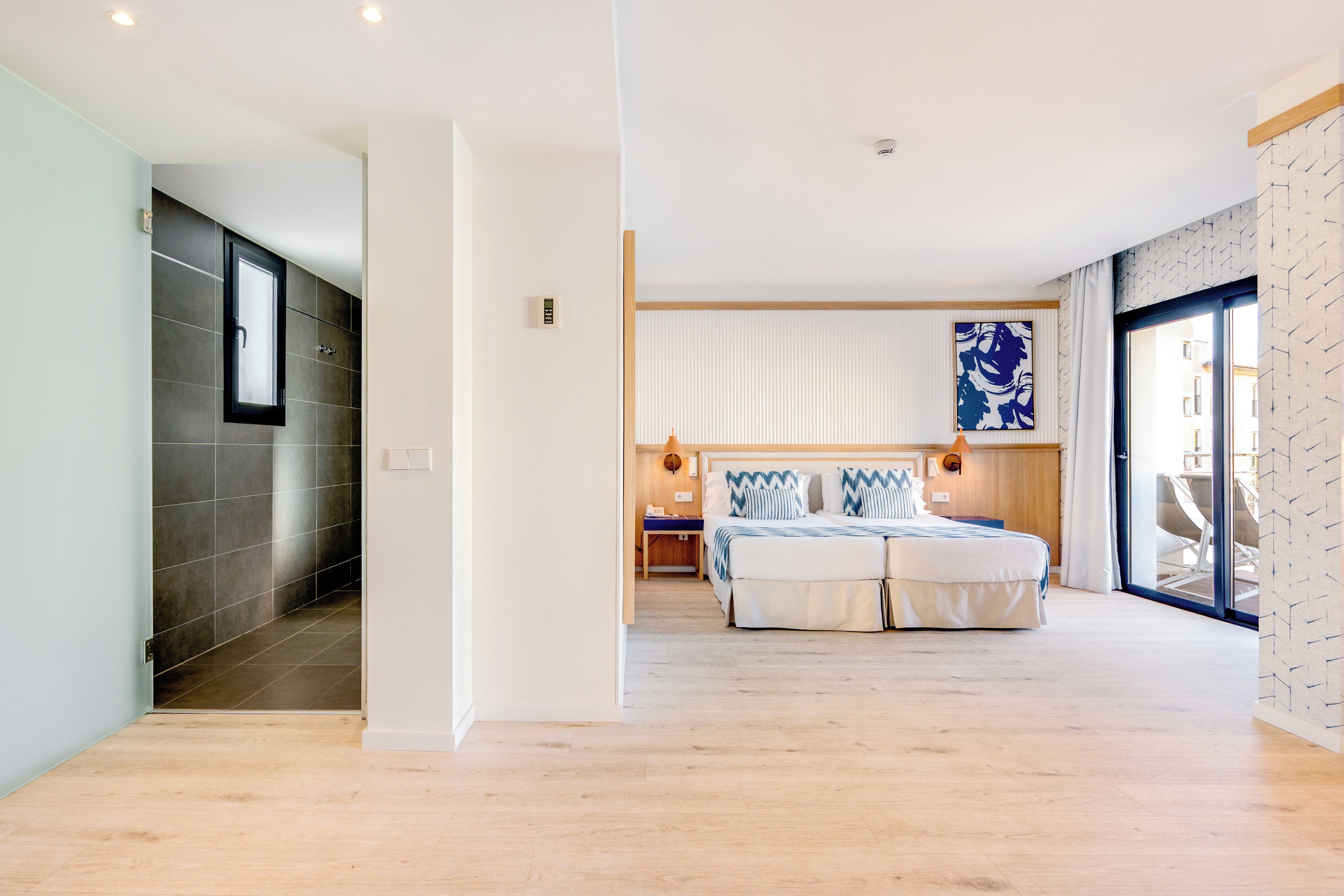 A modern hotel room with a large bed, a desk, and a view of the city.