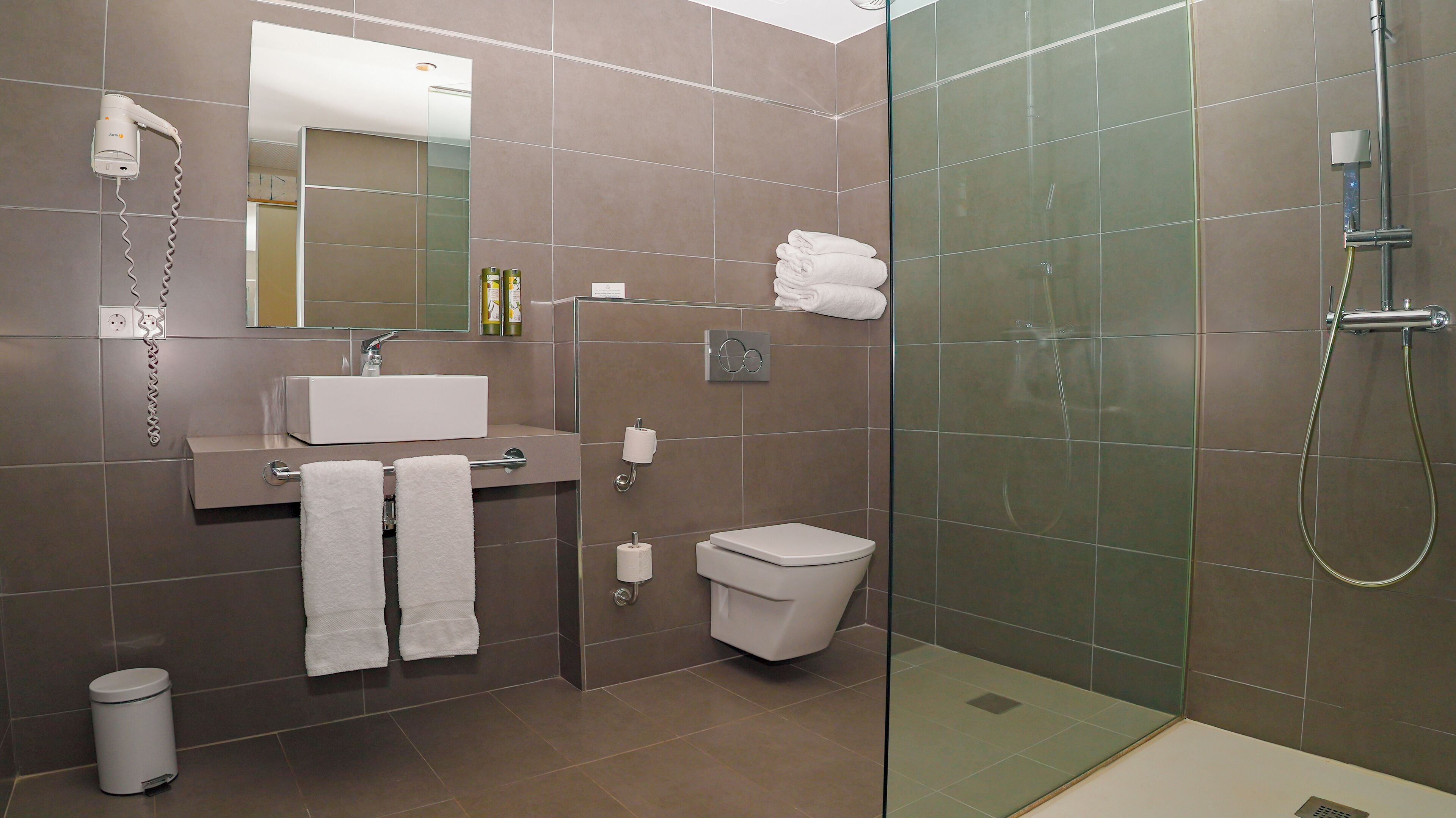 Un baño moderno con cabina de ducha de vidrio, un lavabo con espejo y un inodoro.