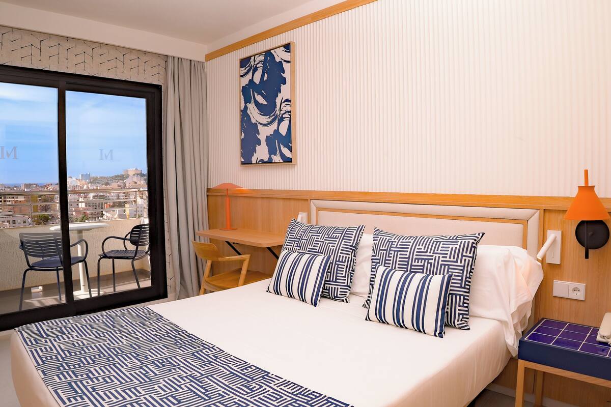Une chambre d’hôtel avec un grand lit, un bureau, une chaise et une vue sur la ville.