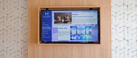 A digital display board in a hotel room with a menu of services including Home, Gastronomy, Hotel services, Spa, External services, IMS Doctor, Television, Netflix, and Cast other app.