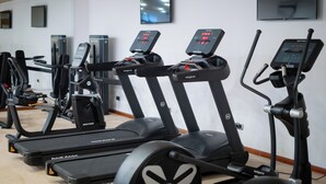 Un gimnasio con cintas de correr, elípticas y una bicicleta estática.