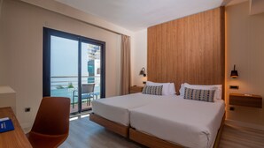 A hotel room with a large bed, a chair, a desk, a nightstand, a lamp, and a view of the outside balcony. - Hotel Isla Mallorca & Spa (Palma de Mallorca)