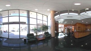 Un vestíbulo amplio con un mostrador de recepción curvo, ventanas grandes y una mesa de centro de vidrio.
