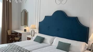 Habitación de hotel con una cama grande, un escritorio, una silla, una araña y una decoración en la pared.