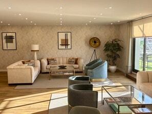 Una sala moderna con sofá, sillones, una mesa de centro y una lámpara de pie.