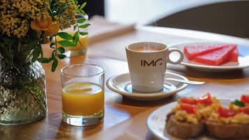 A breakfast setting with a cup of coffee, a glass of orange juice, a plate of toast with toppings, and a vase with flowers.