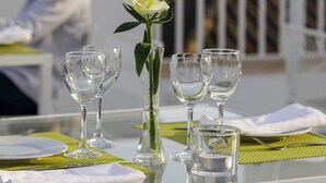A table set for dining with a white tablecloth, a vase with a single white flower, and several wine glasses. - Hotel Fernando III (Seville)