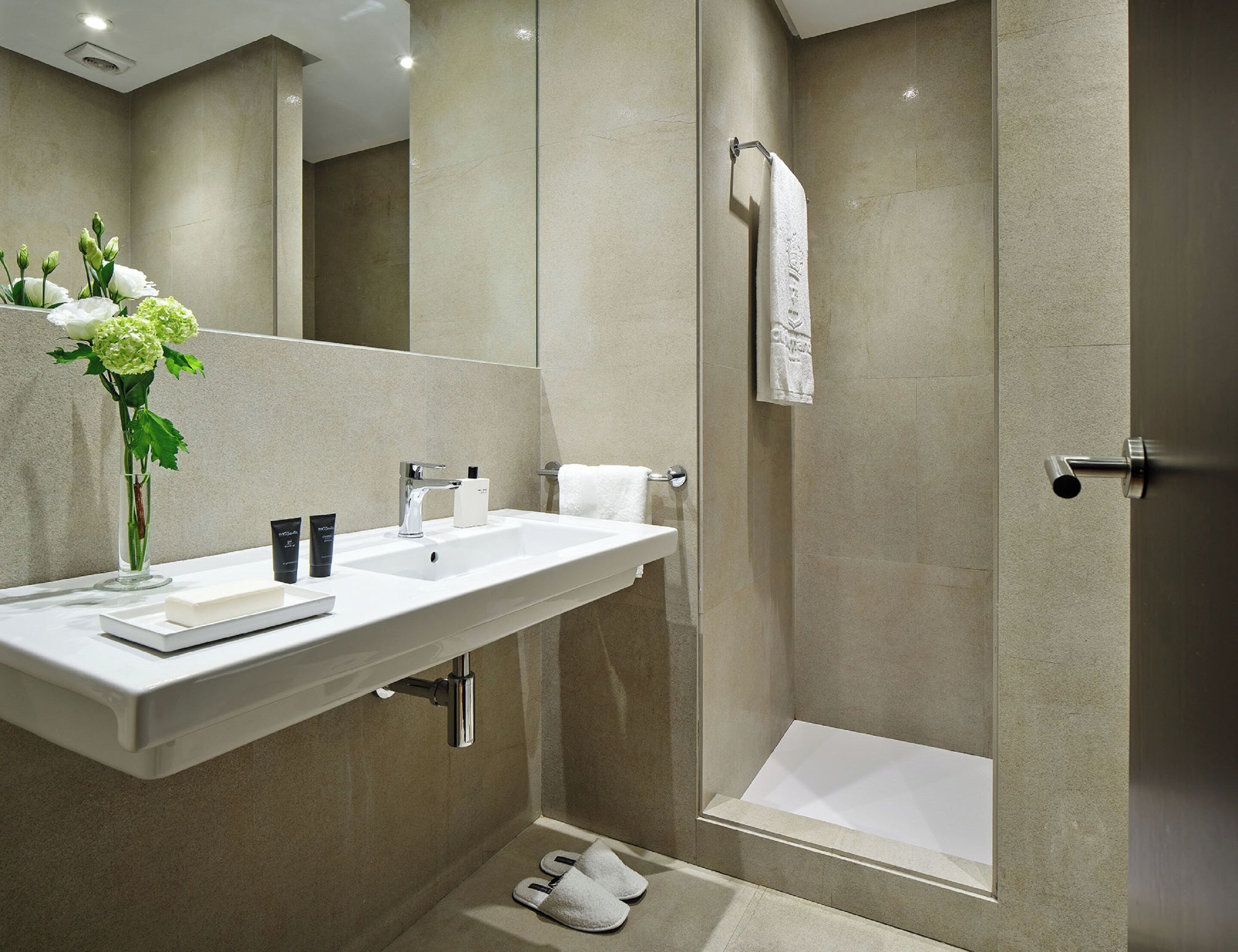 A modern bathroom with a large sink, mirror, and shower.