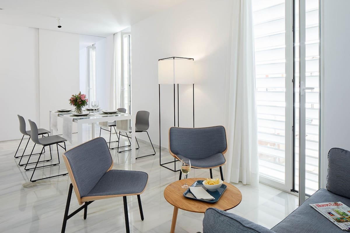 A modern hotel room with a dining area, a sofa, and a floor lamp.