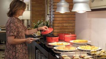 A buffet setup with various food items, including pancakes and sandwiches, and a person serving food.