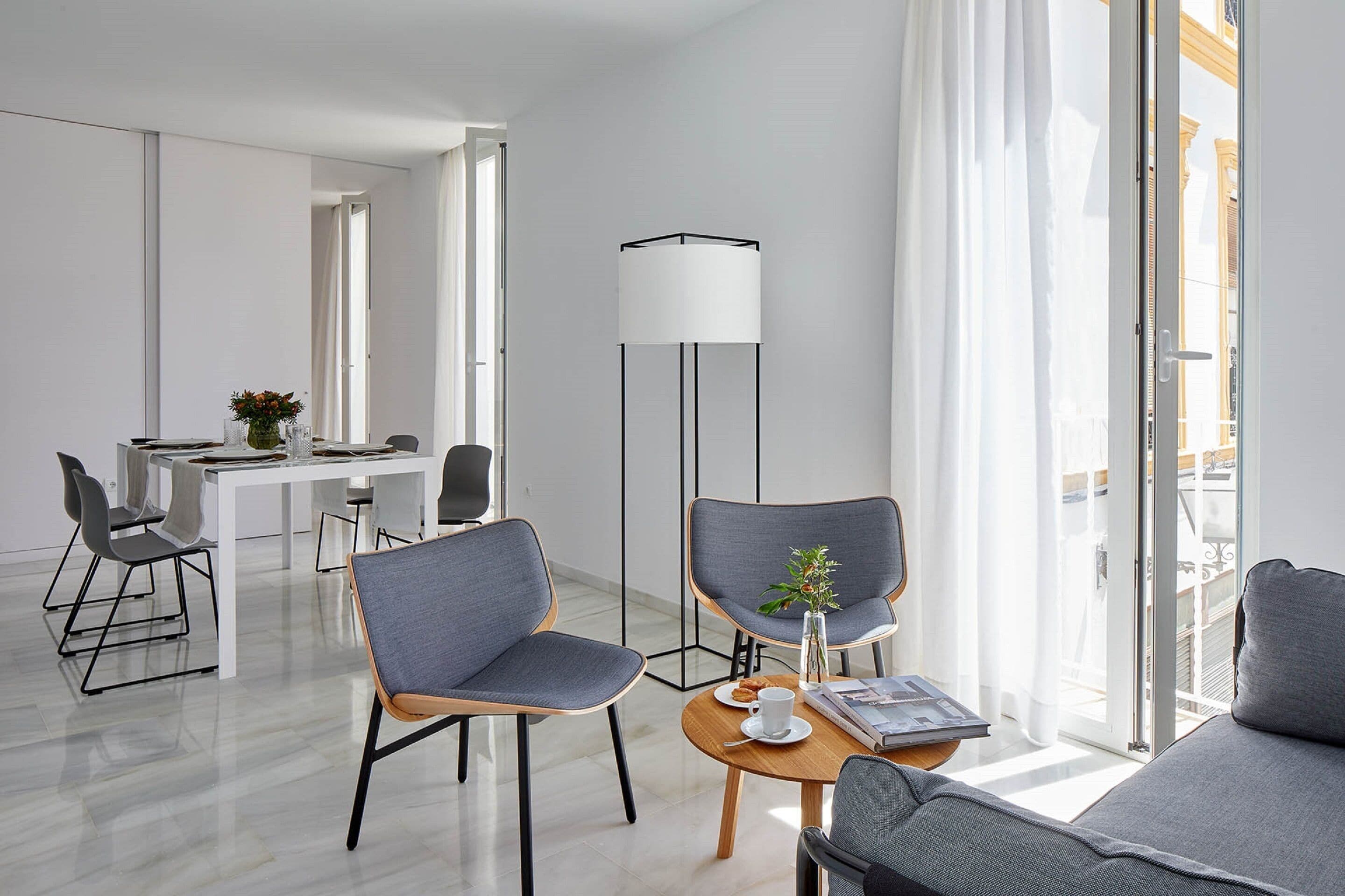 A modern hotel room with a dining area, a sofa, and a floor lamp.