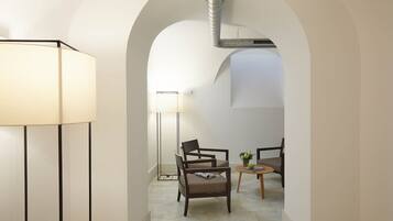 A modern interior with a lamp, two chairs, a small table, and an arched doorway.