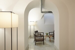 A modern interior with a lamp, two chairs, a small table, and an arched doorway.