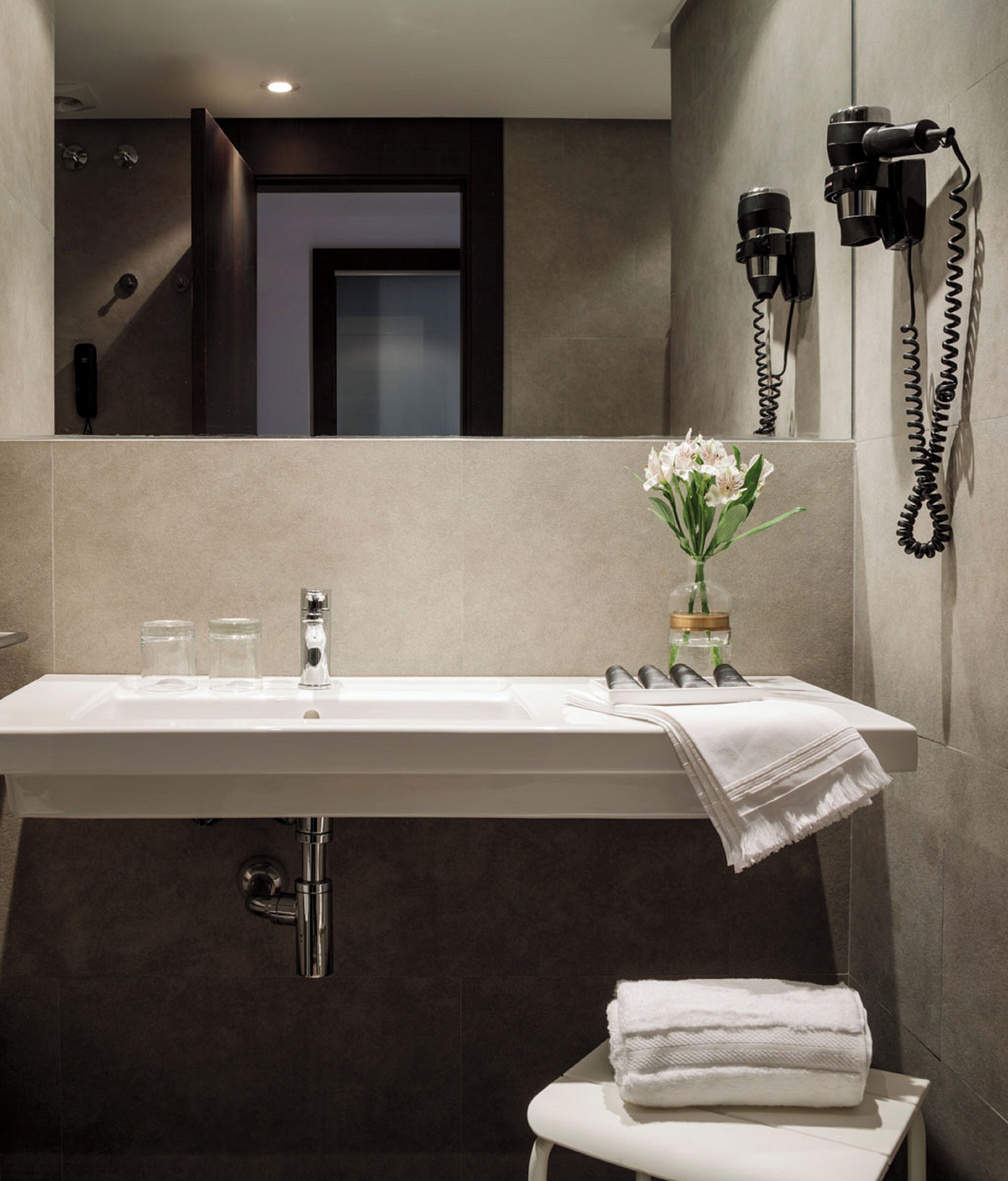 Un baño moderno con un lavabo grande, un espejo, un perchero para toallas y un secador de pelo.