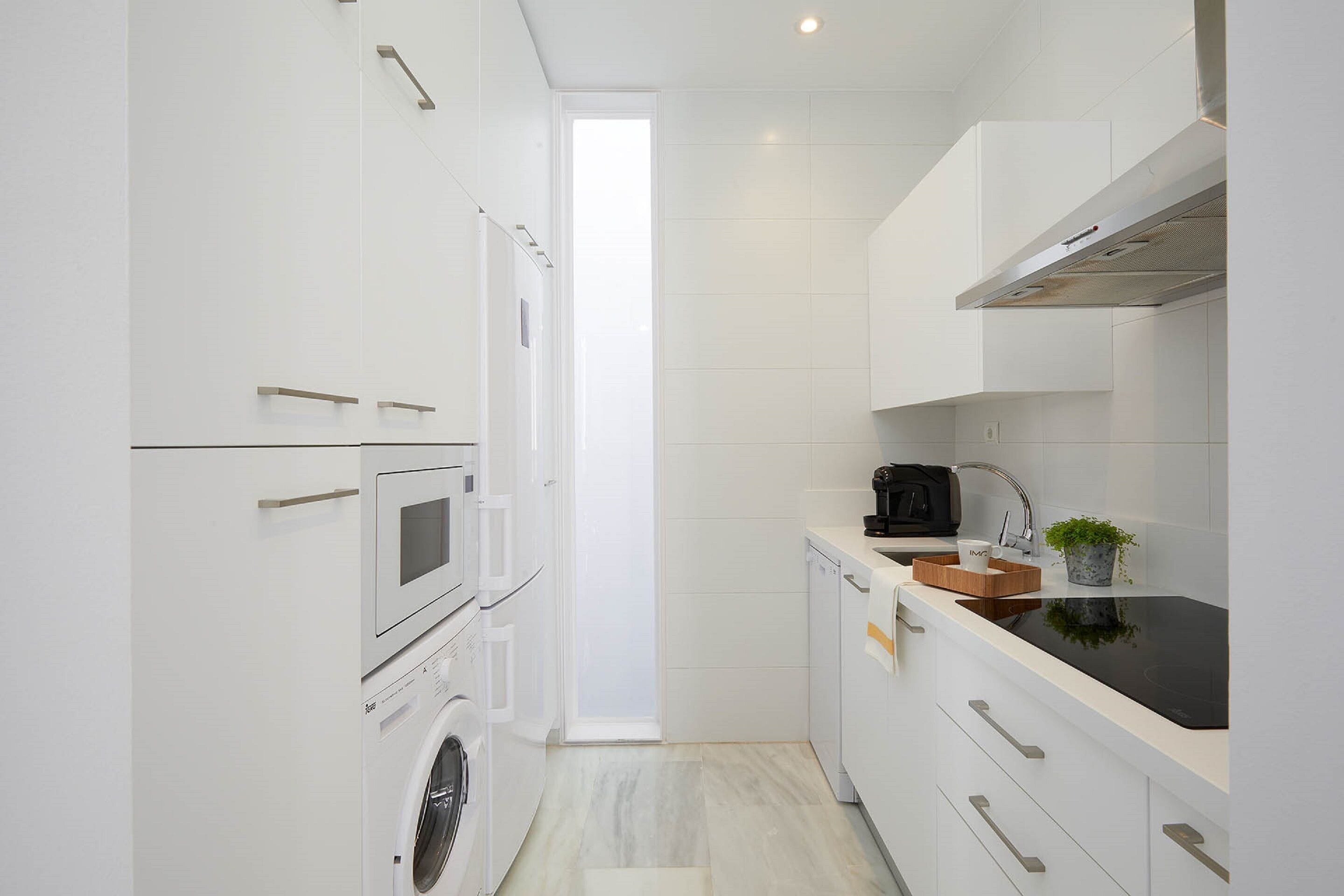 A compact kitchen with white cabinetry, a microwave, a coffee maker, and a small plant.
