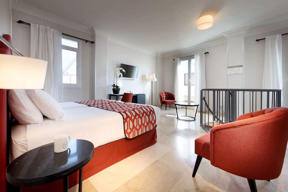 Ein Hotelzimmer mit Bett, Schreibtisch, Stuhl, kleinem Tisch und einem Balkon.