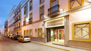 A hotel with a classic European facade, featuring a ground-floor entrance with large windows and a balcony.