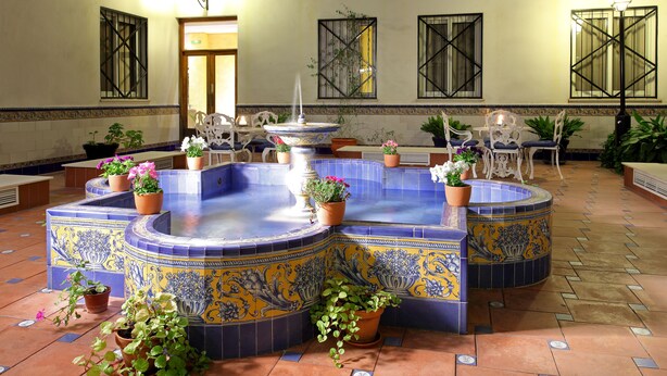 A courtyard with a fountain, potted plants, and outdoor seating.