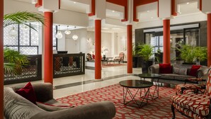 A spacious lobby with a reception desk, seating area, and large windows.