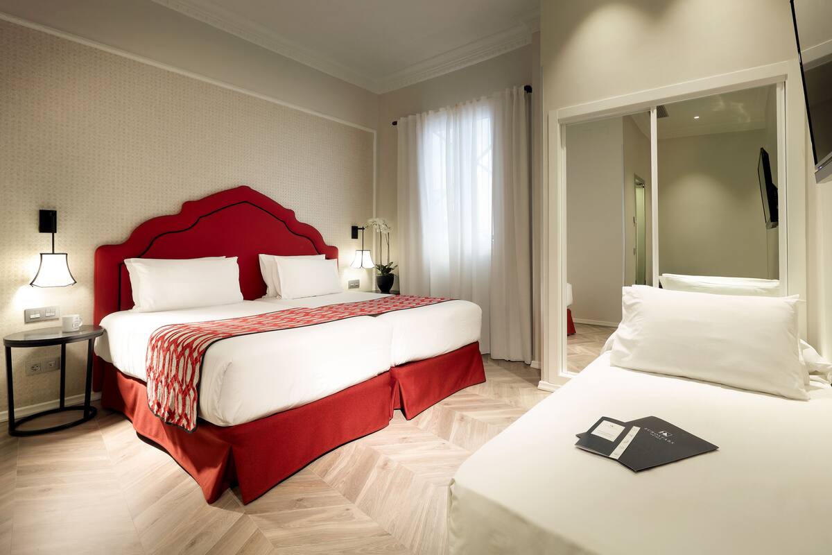 Ein Hotelzimmer mit einem großen Bett, einem Nachttisch, einem Fernseher und einer Tür zu einem Badezimmer.