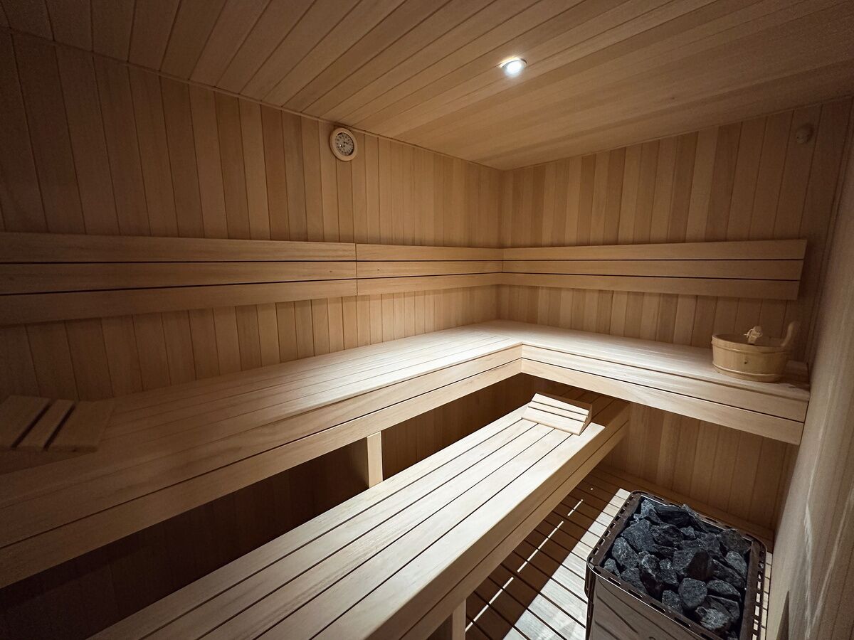 A sauna with wooden benches and a small shelf with a basket.