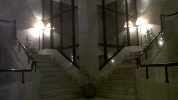 A staircase with glass railings and two wall-mounted lamps.