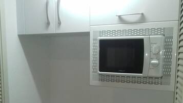 Een keuken met witte kastjes, een granieten aanrecht, een roestvrijstalen spoelbak en een magnetron.