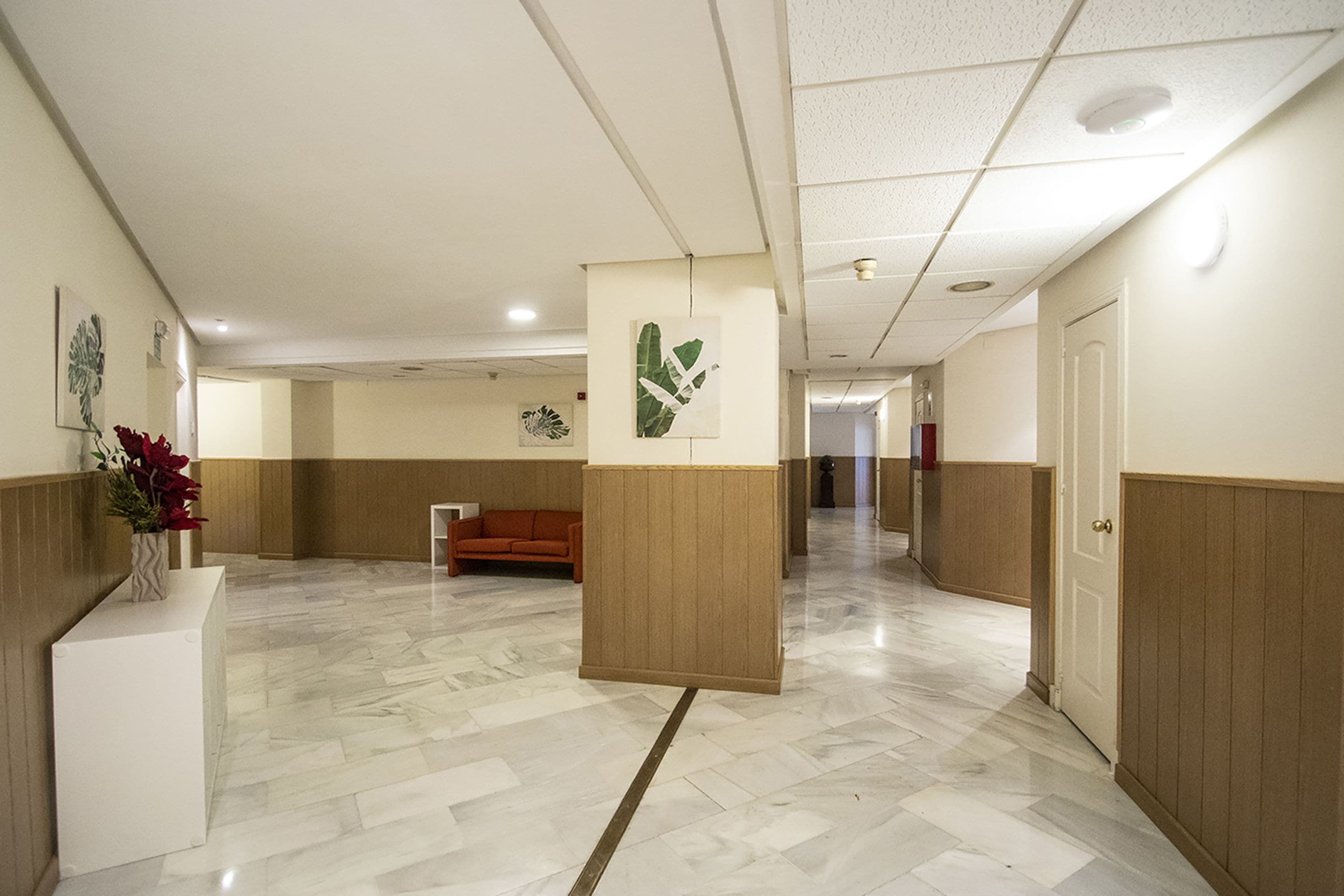 Un hall d’hôtel comprenant un comptoir d’accueil, un canapé et un couloir menant à d’autres espaces.