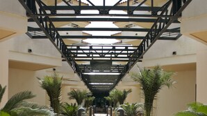 A corridor with tiled flooring, potted plants, and a staircase with a metal railing.