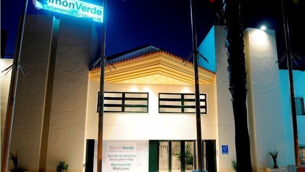 A hotel entrance with a sign reading "Simón Verde" and a welcome message.