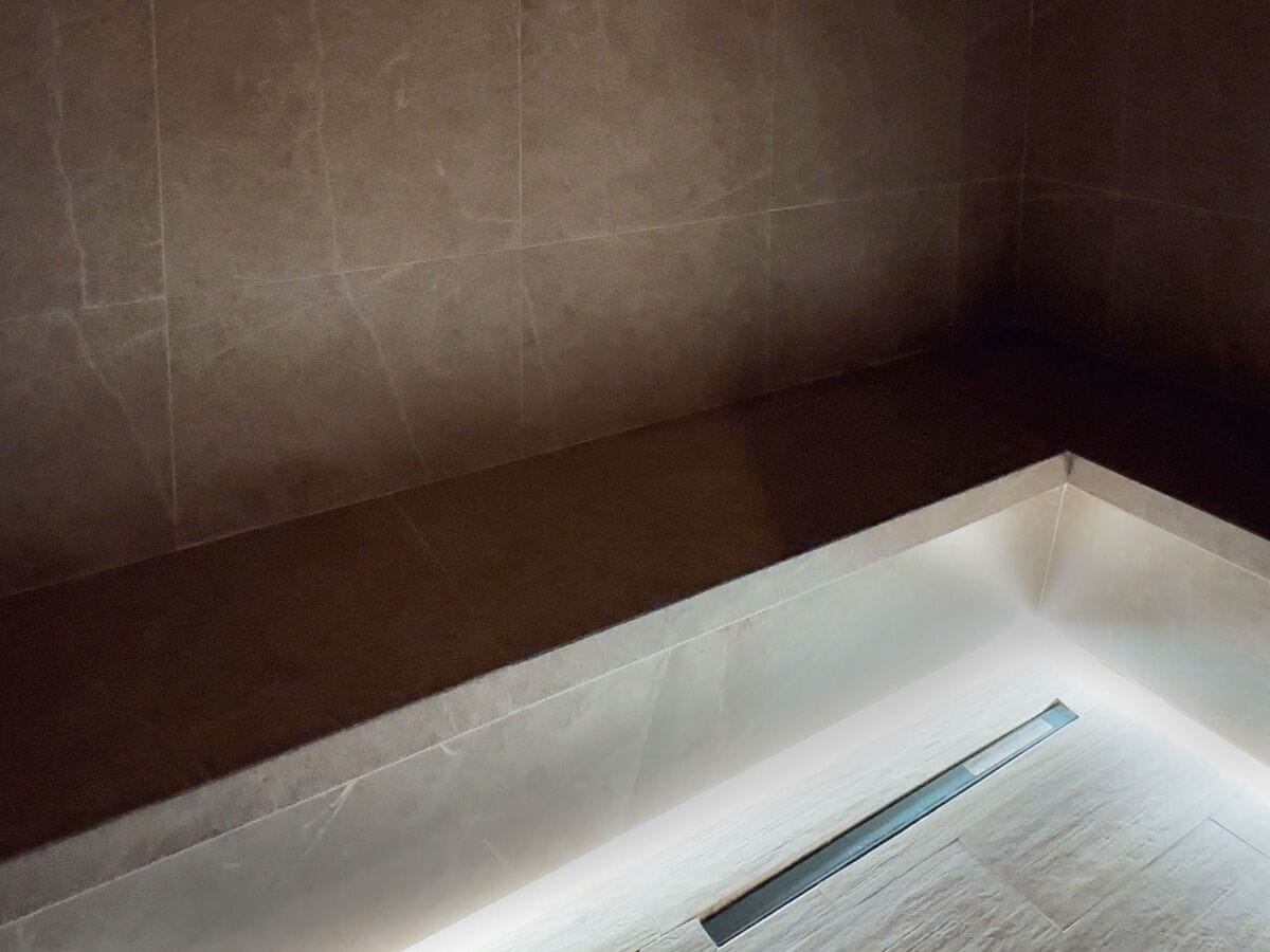 A modern bathroom with a large bathtub, a visible drain, and a light fixture above the tub.