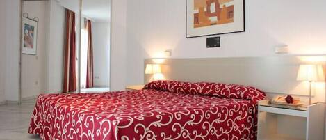 A hotel room with a bed, two bedside lamps, a nightstand, and a framed picture on the wall.