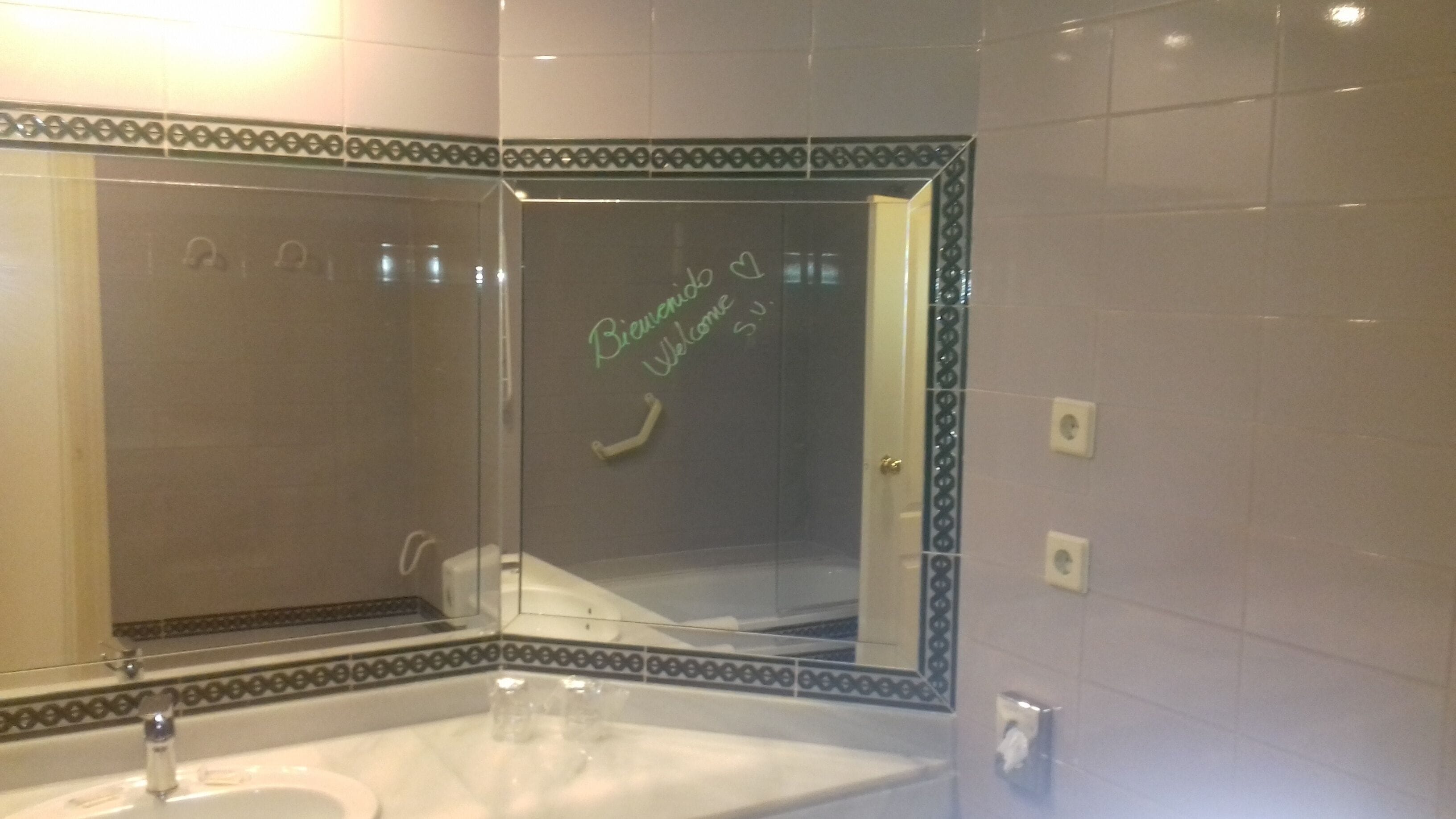 Une salle de bain avec un grand miroir, un lavabo et un porte-serviettes.