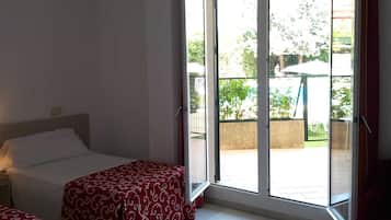 Une chambre à coucher avec un lit, une fenêtre et une vue sur un espace extérieur aménagé avec une table et des chaises.