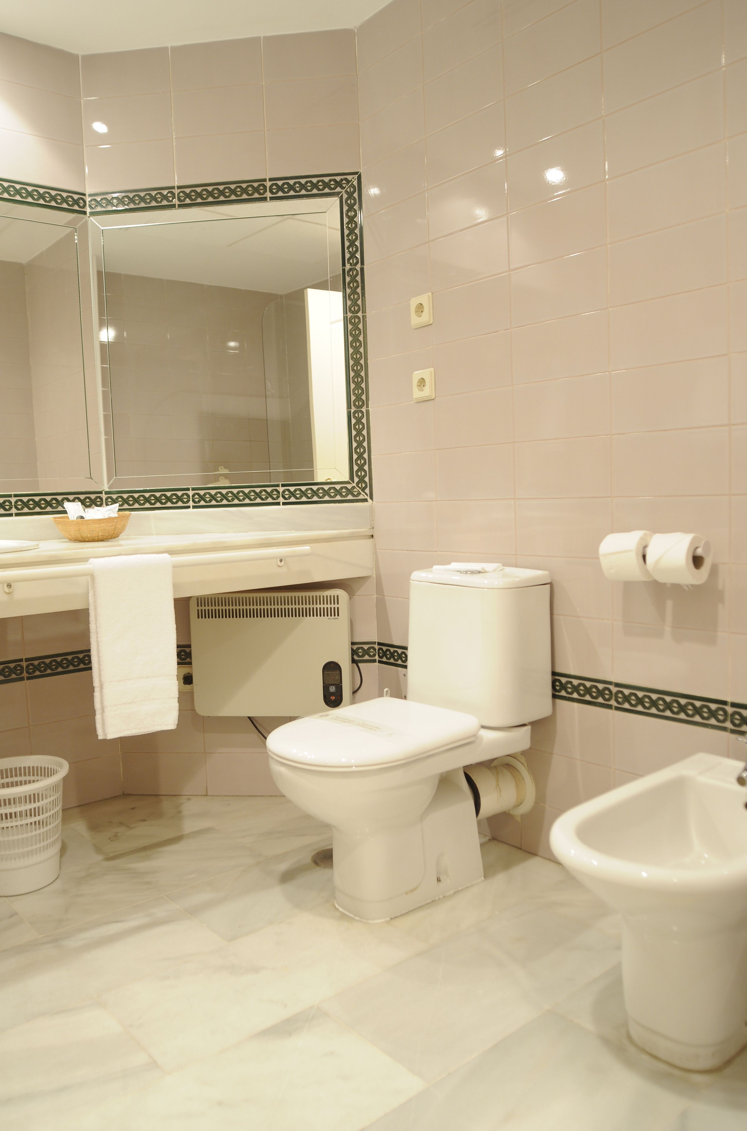 Et badeværelse med toilet, bidet og et stort spejl.
