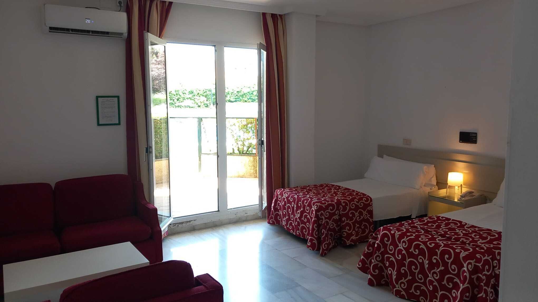Habitación de hotel con cama, escritorio, silla y vistas al exterior.