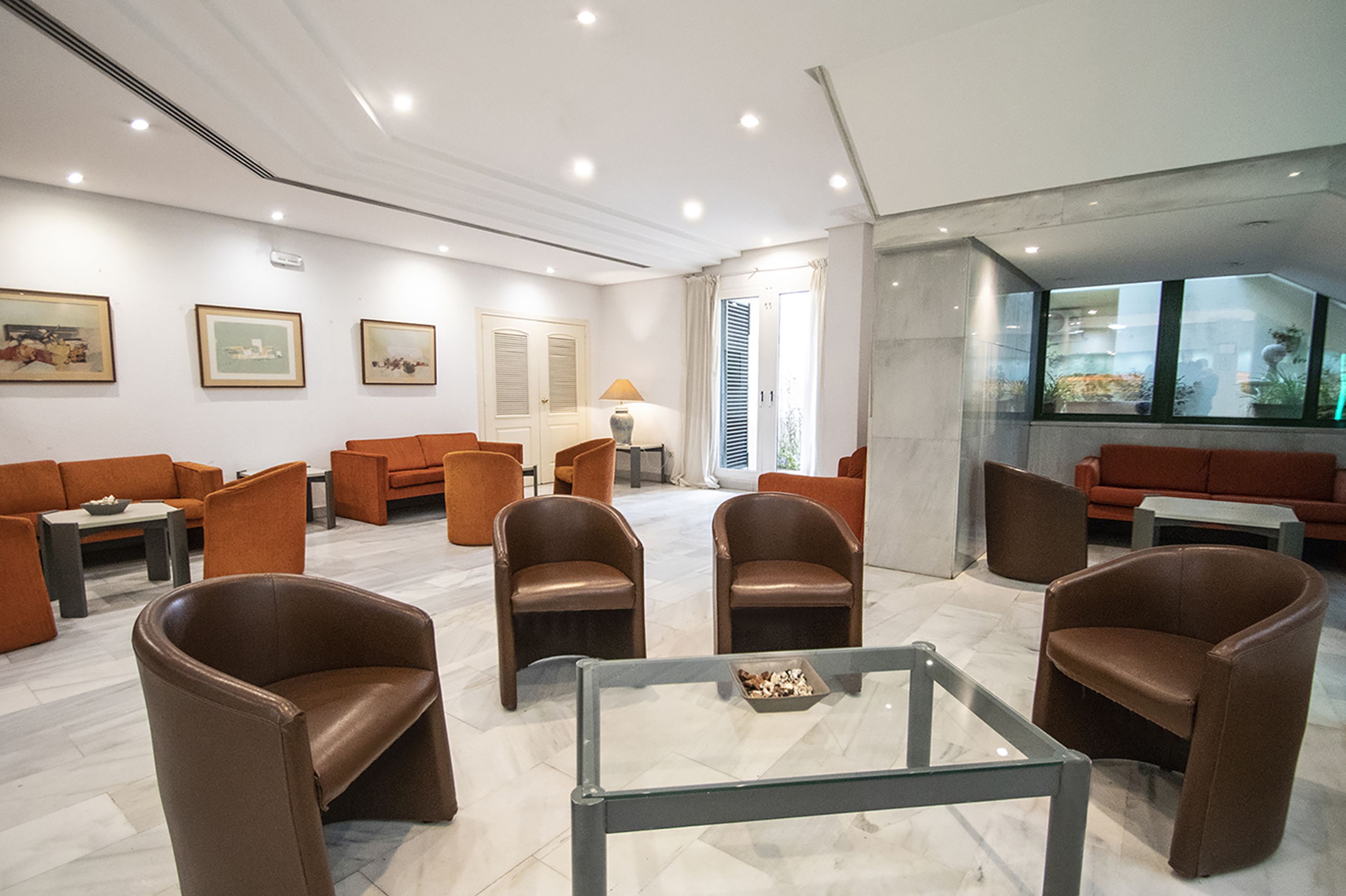 A modern lobby with leather sofas, a glass coffee table, and framed artwork on the walls.