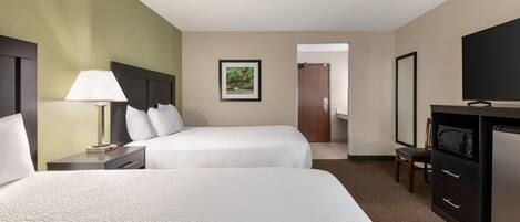 A hotel room with two beds, a TV, a microwave, and a framed picture on the wall.