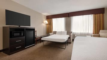 Habitación de hotel con cama, escritorio, televisión, microondas y minibar.