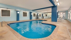 An indoor swimming pool with a blue interior, tiled floor, and a seating area with chairs and tables. - Baymont by Wyndham Rockford (Rockford)
